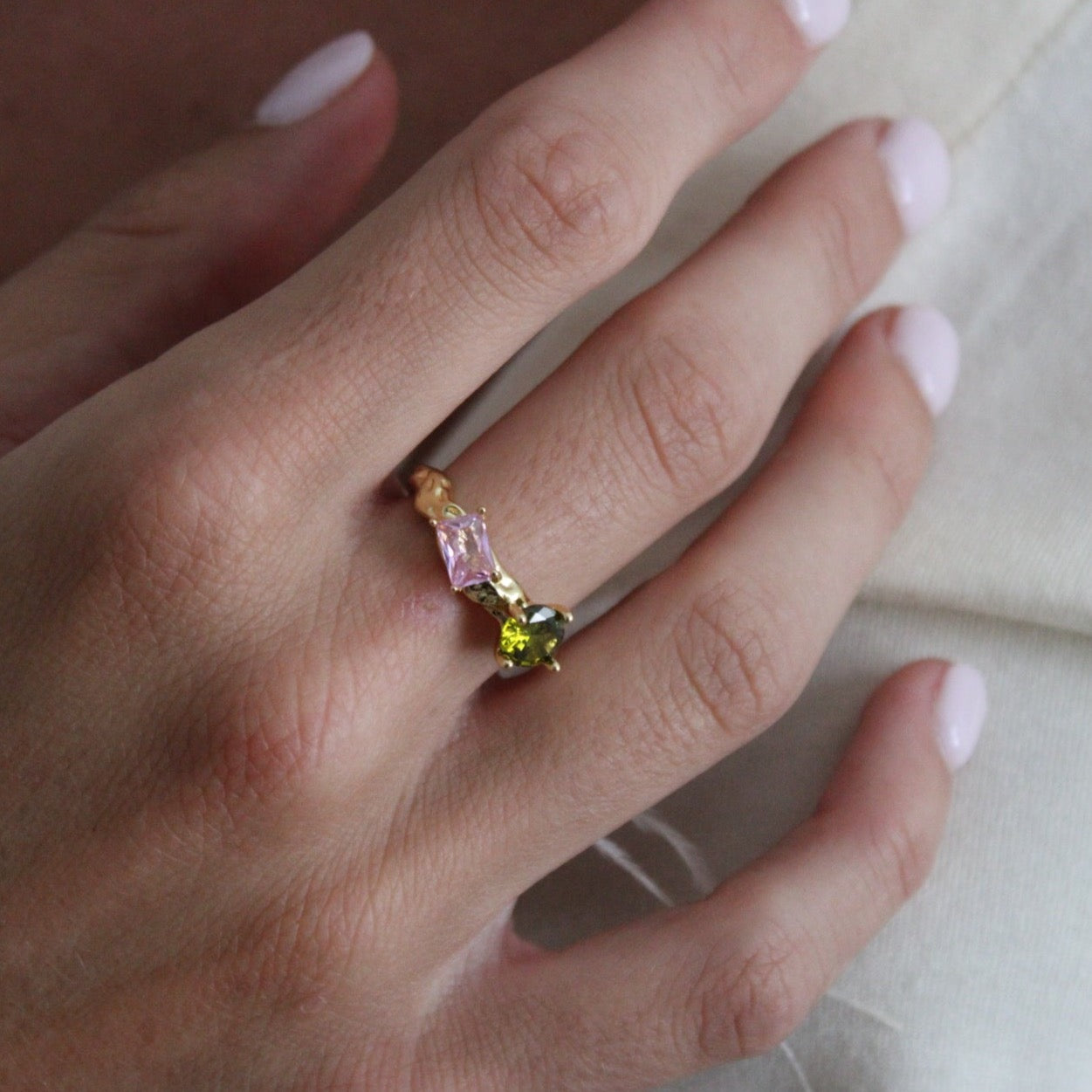 Gold filled adjustable ring with pink and green gems on it